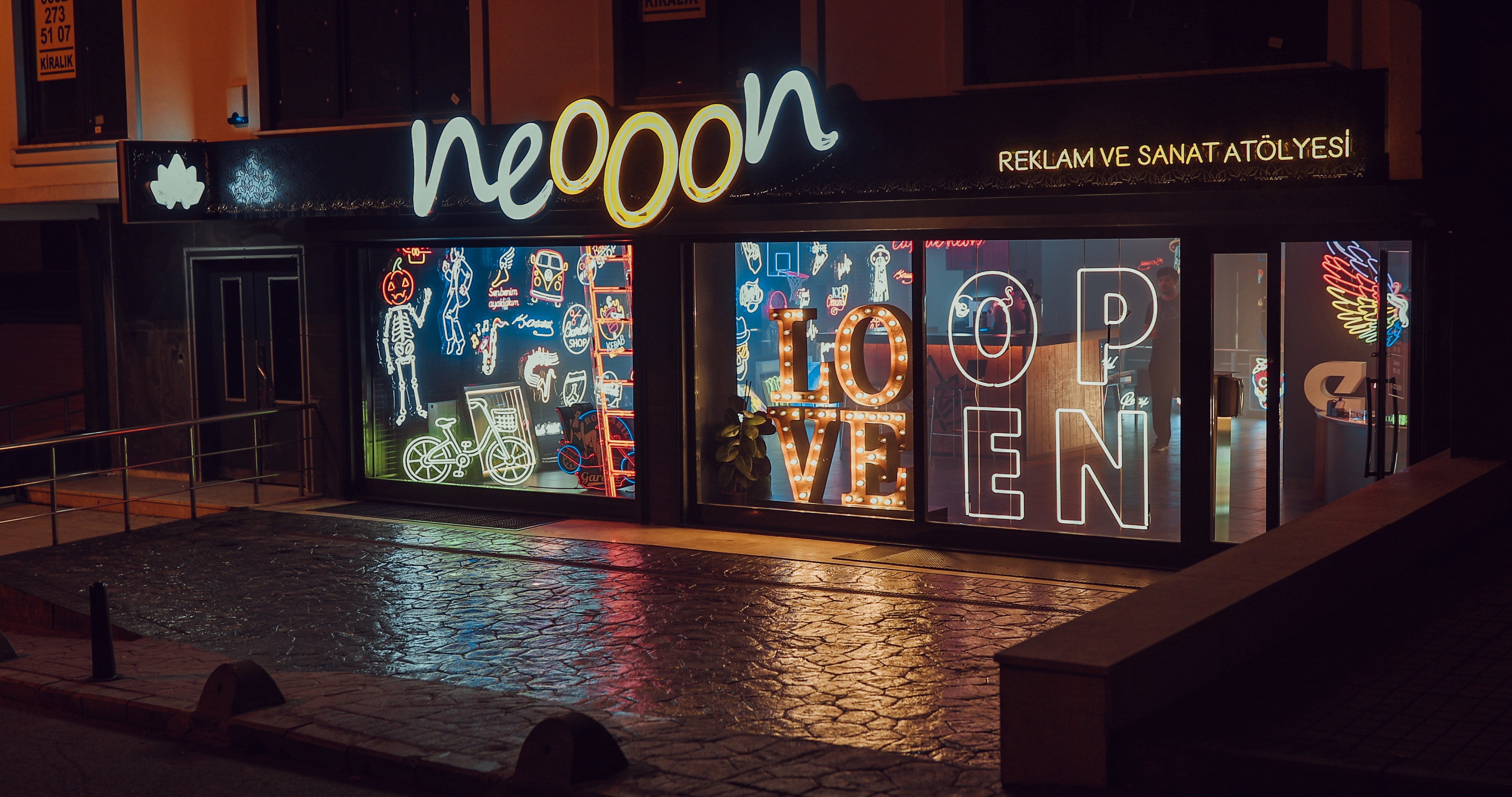 Außenfassade der Neooon-Boutique mit leuchtendem Neon-Logo und modernem Design.